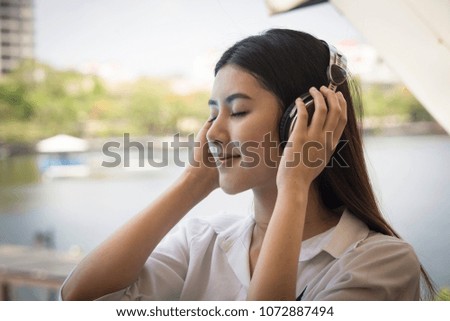 Young Thai girl using headphones outdoors