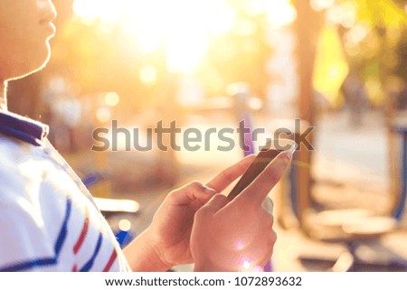 a man check mobile phone and light sunset with blur background. 