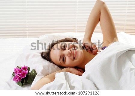 Caucasian woman lying in a bed of flowers on a light background