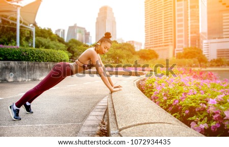 Pretty Young Fit Woman doing push ups Outdoor Warmup in Summer Side view. Female Workout before Training Session at the Park with Montreal Skyline in Background.