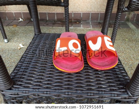 Red used slippers with white love letters put on wicker desk.Love couple concept.