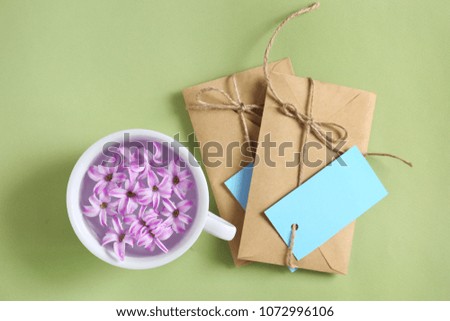 Cup with flowers and mail envelopes on color background