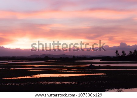 Natural Sunset Sunrise Over Field Or Meadow. Bright Dramatic Sky And Dark Ground. Countryside Landscape Under Scenic Colorful Sky At Sunset Dawn Sunrise. Sun Over Skyline