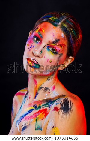 fashion portrait of a brunete model painted skin, strokes of paint-brush on skin, black background with red lights