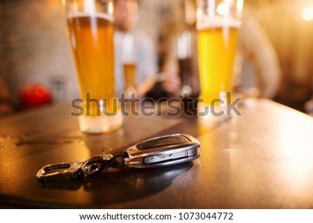 Close up focus view of car keys on the bar table in front of glasses with draft beer.