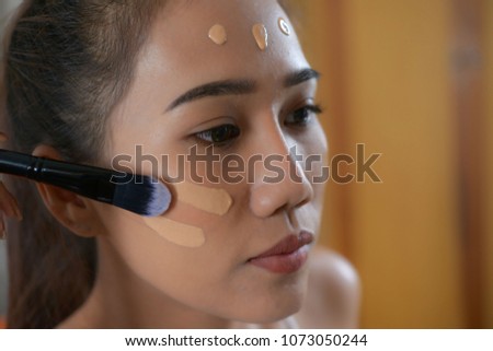 Asian woman applying foundation  on her face for beauty.