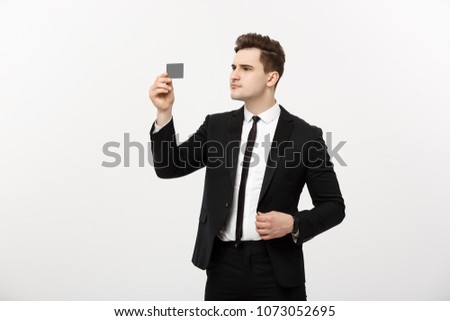 Portrait of a businessman holding a credit card and seriously checking isolated over grey background.