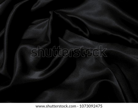 Black fabric texture background, wavy fabric slippery black color, luxury satin cloth texture for 
luxurious background or wallpaper.