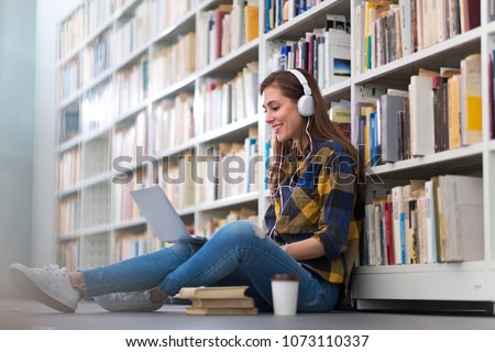 Young female student studying in the library Royalty-Free Stock Photo #1073110337