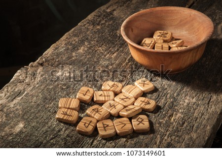 Runes in a wooden plate on a textured old textured wooden surface