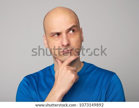 middle aged bald man looking up and thinking. Isolated on grey. Studio shot Royalty-Free Stock Photo #1073149892