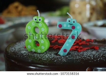 Close up view of candles with cartoon numbers shapes on a cake for birthday celebration. Background of foods for birthday party.