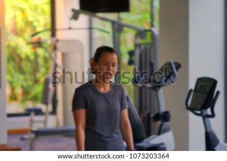 Asian girl feel tired after trainning in fitness room in blur photo