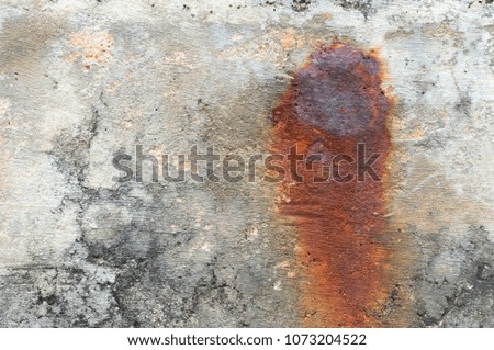 Old concrete wall texture background with dark red burn in the middle caused by rust nail