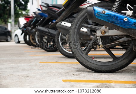 Motorcycle parking in the right way and orderly.Bikes are parked in a parked area separated by yellow lines. Take close-up shots to the moped wheel.