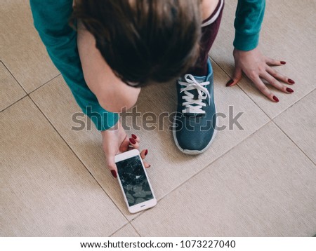 Girl with broken screen smartphone on the tile floor.