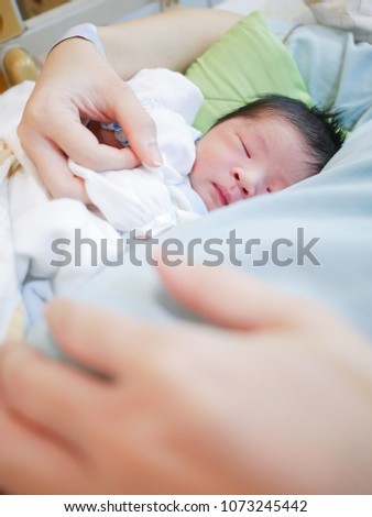 Loving baby  day 1 old sleeping in mother's hands. Closeup picture. Happy mother and her slipping newborn baby in the bed