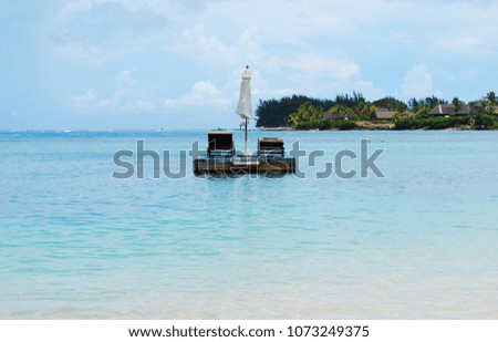 Chaise lounges and white sun umbrella in the sea on a pantone, azure sea and blue sky with clouds, Mauritius island