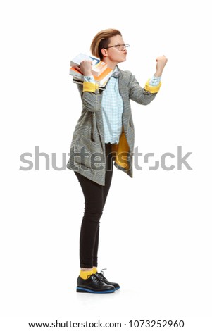 Full length portrait of angry, violent, enraged female student in glasses holding books isolated on white background. Female figure of caucasian model at studio. 