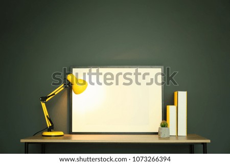 Mockup of blank frame and lamp on table