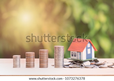 View Of coin stack with house model on green background, savings plans for housing, financial concept,Mortgage loading real estate property with loan money bank concept.Property Tax Concept