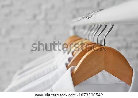 Rack with clean clothes on hangers after dry-cleaning, closeup Royalty-Free Stock Photo #1073300549