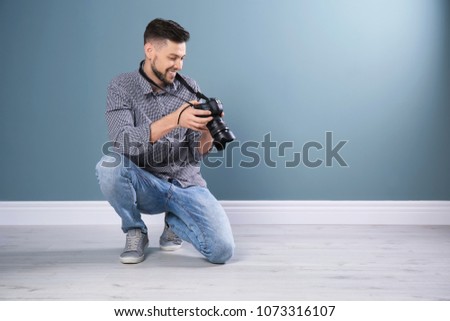 Male photographer with camera near grey wall
