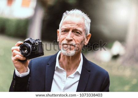 Mature man taking pictures outdoors, light effect