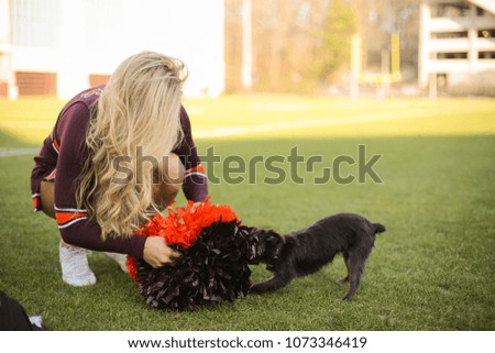 Cheerleader Trying to get her pom poms back from a small dog