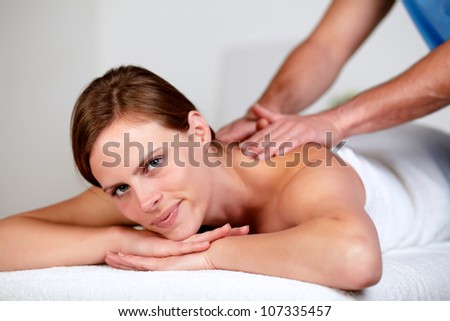 Close-up portrait of a pretty young blonde woman relaxing at a spa while receiving a massage at spa resort looking at you