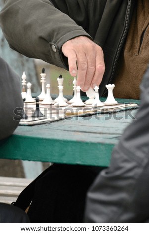 Active people in their free time on vacation with pleasure playing chess on the street. Figures and chess board close-up.