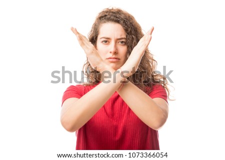 Serious woman making X sign with her arms to stop doing something on white background