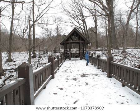 Girl standing on snow covered bridge taking pictures