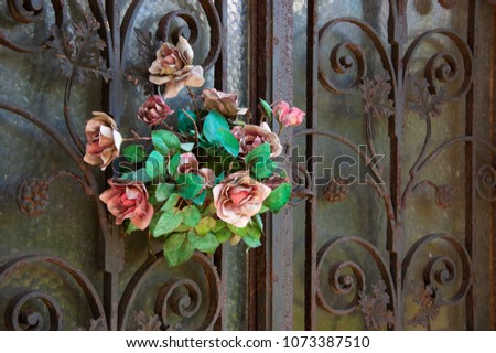 Old cemetery. Faded rose wreath hanging on tomb door.