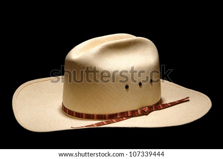 Traditional and authentic American West rodeo cowboy white straw hat with decorative band isolated on pure black background