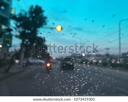 Blurred background, water drops on the windshield, traffic in the city on a rainy day at evening, colorful bokeh.