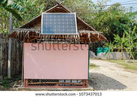 Solar cells on the roof of a hut at the plate. It is in the garden and has a green tree background.