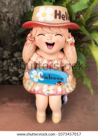 Little girl doll smile with welcome sign.