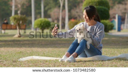 Woman taking selfie by mobile phone with her dog 