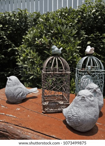Birds sculpture and cage in garden. Vintage photo background