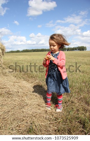 girl in denim dress and bright striped tights in windy weather in the field