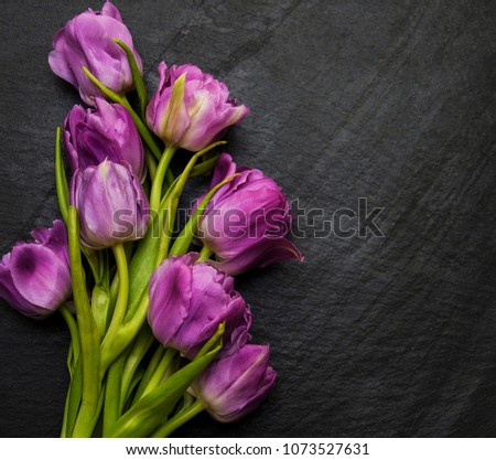 Spring tulip flowers on a black stone table