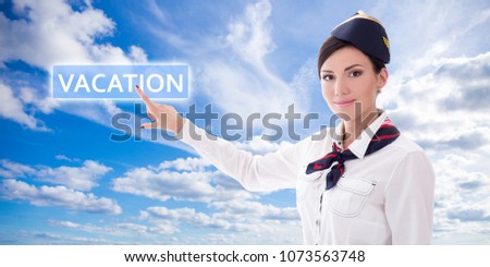 travel concept - stewardess in uniform pointing at vacation button over blue sky background