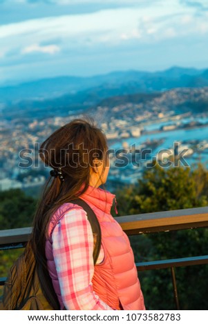 Asian woman looking out of sea side city.