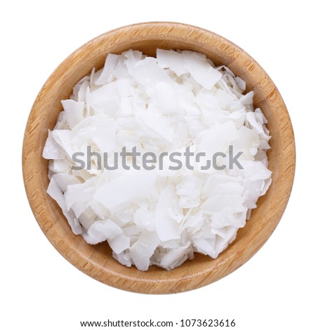Organic raw coconut chips in wooden bowl isolated on white. Top view. Royalty-Free Stock Photo #1073623616