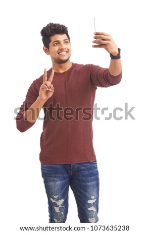 Handsome Indian young man taking selfie in mobile phone on white