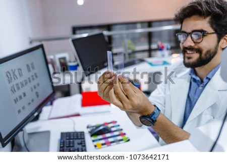 Researcher in the lab looking on microscope slide. Works with the microscope slide.  Attractive young male scientist looking at the microscope slides in laboratory.