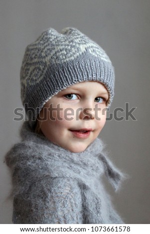 Portrait of a girl in a knitted double-sided jacquard white-gray hat and fluffy gray shawl