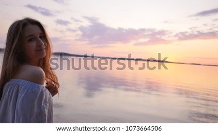 Young girl on the background of the sea and sunset.