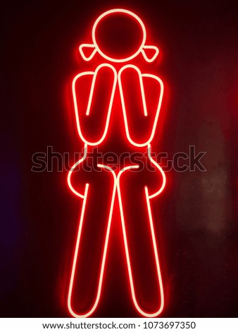 Female toilet sign with red neon on black background